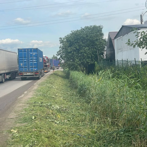 Покос травы по краю проезжей части, покос высокой травы и бурьяна в канаве в Санкт-Петребурге